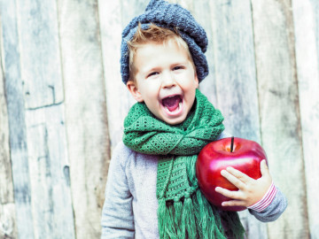 Junge mit übergroßem Apfel im Arm