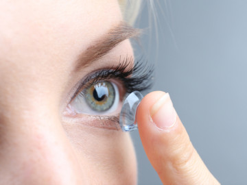 Frau setzt eine Kontaktlinse ein