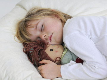 Schlafendes Mädchen mit Puppe im Arm