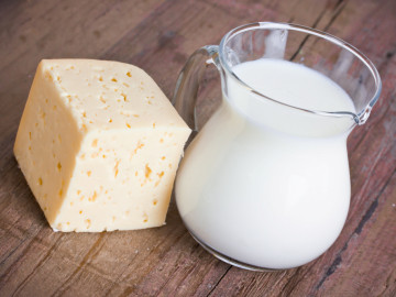 Käse und ein Krug Milch auf einem Holztisch