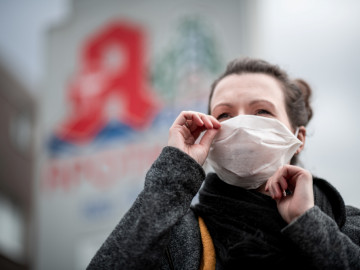 Frau mit Mundschutz vor Apotheke