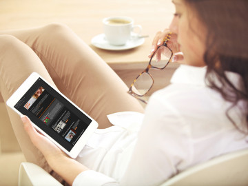 Frau schaut sich den Newsletter von DAS PTA MAGAZIN im Dark Mode auf dem Tablet an