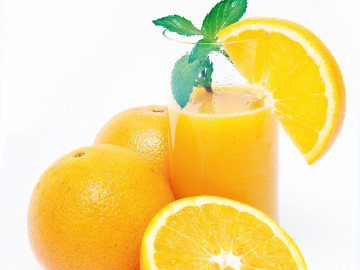 Frisch gepresster Organgensaft im Glas mit Orangen und einer aufgeschnittenen Fruchthälfte 