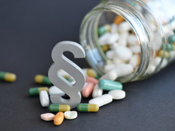 Paragraph vor umgekipptem Glas mit Tabletten