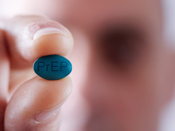 Mann hält fiktive PrEP-Tablette zwischen zwei Fingern