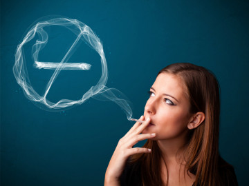 Junge Frau raucht. Der Rauch bildet ein „No-Smoking-Symbol“.