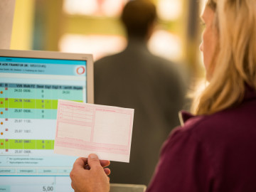Apothekenangestellte vor dem Computer mit Rezept in der Hand