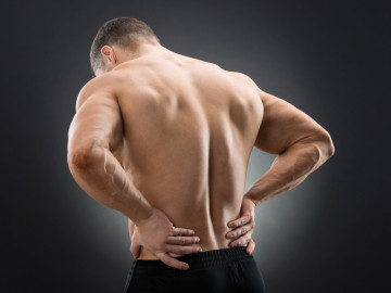 Muskulärer Mann hält sich den Rückenbereich