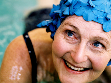 Seniorin im Schwimmbad mit blauer Badekappe
