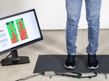 Person steht auf Sensormatte, Monitor zeigt Belastung an