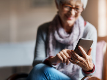 Seniorin blickt aufs Smartphone