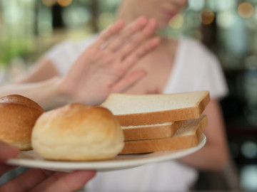 Frau lehnt per Hand angebotenes Weißbrot ab