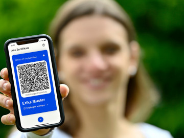 Frau hält Smartphone mit QR-Code für das Impfzertifikat in die Kamera