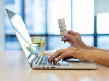 Laptop, Person mit Tabletten in der Hand