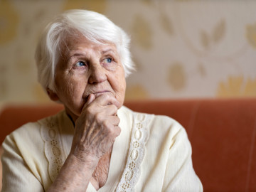 Nachdenkliche Seniorin auf einem Sofa