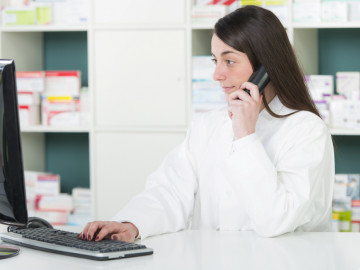 PTA am Computer mit Telefon am Ohr
