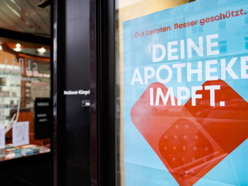 Apothekenschaufenster mit Plakat „Deine Apotheke impft.“