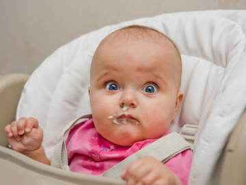 Baby mit breiverschmiertem Gesicht schaut in die Kamera.