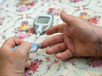 Seniorin überprüft mit einem Glukosemessgerät ihren Blutzuckerwert
