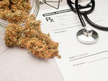 Getrocknete Cannabisblüten und Stethoskop liegen auf einem mit Rx gekennzeichnetem Blatt