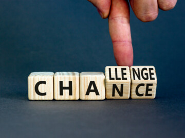 Finger kippt zwei Würfel die aus dem Wort „Chance“ das Wort „Challenge“ bilden