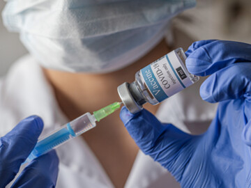 COVID-19-Impfstoff wird auf Spritze gezogen