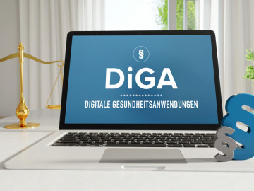 Aufgeklappter Laptop mit Anzeige „DIGA – Digitale Gesundheitsanwendungen“, Paragrafen, goldene Waage