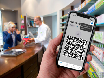 Handy mit eRezept und QR-Code, im Hintergrund Beratungssituation in der Apotheke