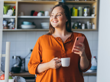 Frau mit Handy und Kaffeetasse