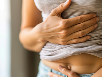 Junge Frau hält sich Magen und Bauch