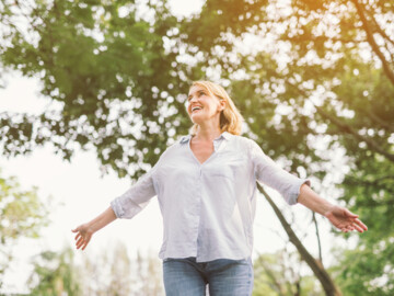 Frau mit offenen Armen in der Natur