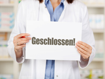 Frau hält ein Schild in den Händen. Darauf steht „Geschlossen!“