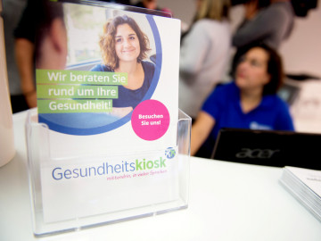 Broschüre "Gesundheitskiosk" im Aufstellr auf einem Schreibtisch