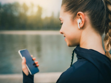 Lächelnde Frau mit Handy in der Hand vor einem See