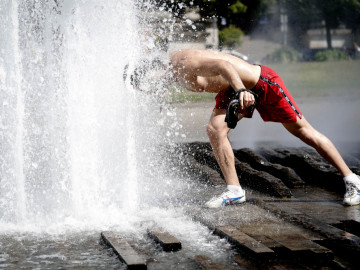 Mann erfrischt sich im Brunnen bei hohen Temperaturen