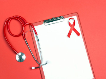 Klemmbrett mit Papier, roter Aids-Schleife und Stethoskop
