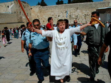 weiß gewandete Frau umgeben von Polizisten in Jerusalem