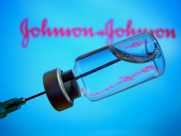 Impffläschchen mit Spritze, im Hintergrund Schriftzug Johnson & Johnson