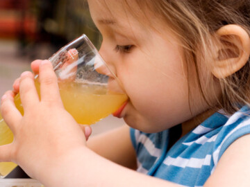Kind trinkt Apfelsaft aus einem Glas