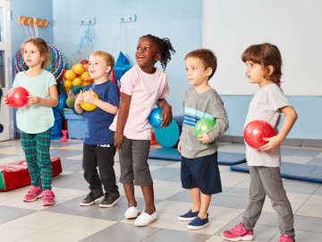 Gruppe von Kindern in der Turnhalle mit bunten Bällen