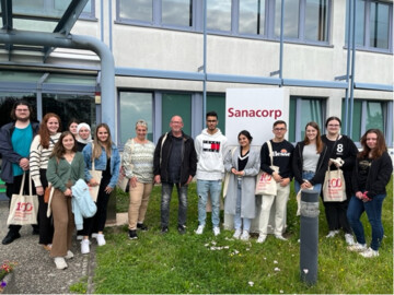Besuchergruppe vor dem Gebäude des Pharmagroßhandels Sanacorp. 