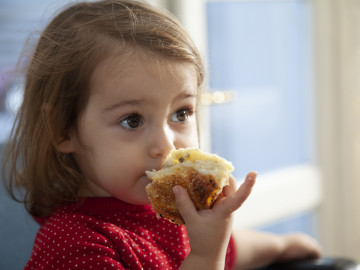 kleines Mädchen hält Brötchen in der Hand