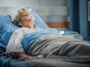 Frau mit Atemmaske im Krankenhausbett