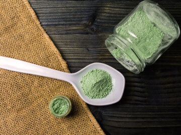 Kratompulver auf einem weißen Keramiklöffel und in einem umgekippten Glas