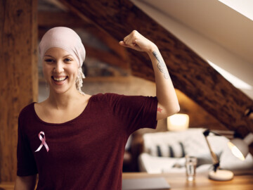 lachende Frau mit Kopftuch (Chemo) und rosa Schleife