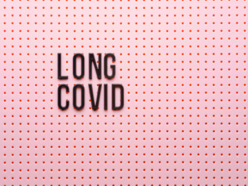 Rosafarbener Hintergrund mit Löchern und Aufschrift „LONG COVID“