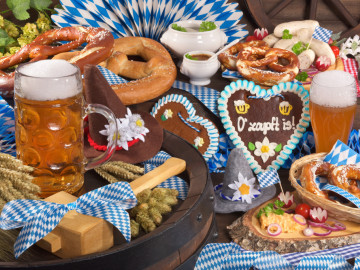 Typisch fürs Oktoberfest: Masskrug mit Bier, Weißwurst, Brezel und Lebkuchenherz mit Aufschrift „O’zapft ist“