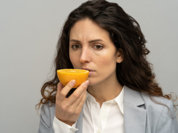 Frau riecht an Orangenhälfte