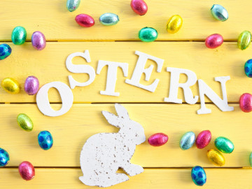 Schriftzug Ostern umgeben von bunten Schokoladenostereiern