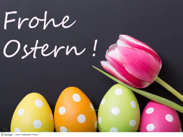 Tafel mit Aufschrift „Frohe Ostern“, vier bunte Eier mit weißen Punkten und eine rosa-weiß-farbene Tulpfe